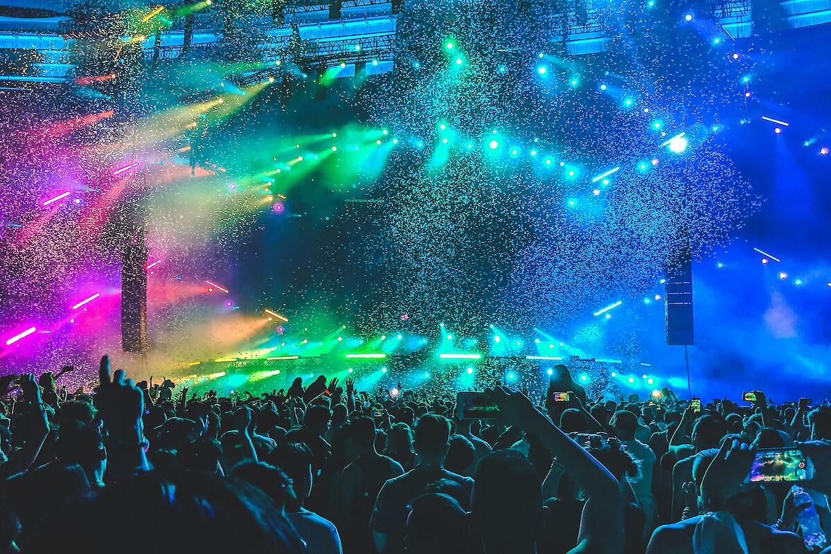A vibrant concert scene with colorful lights, confetti, and a crowd holding up phones, capturing the lively atmosphere.
