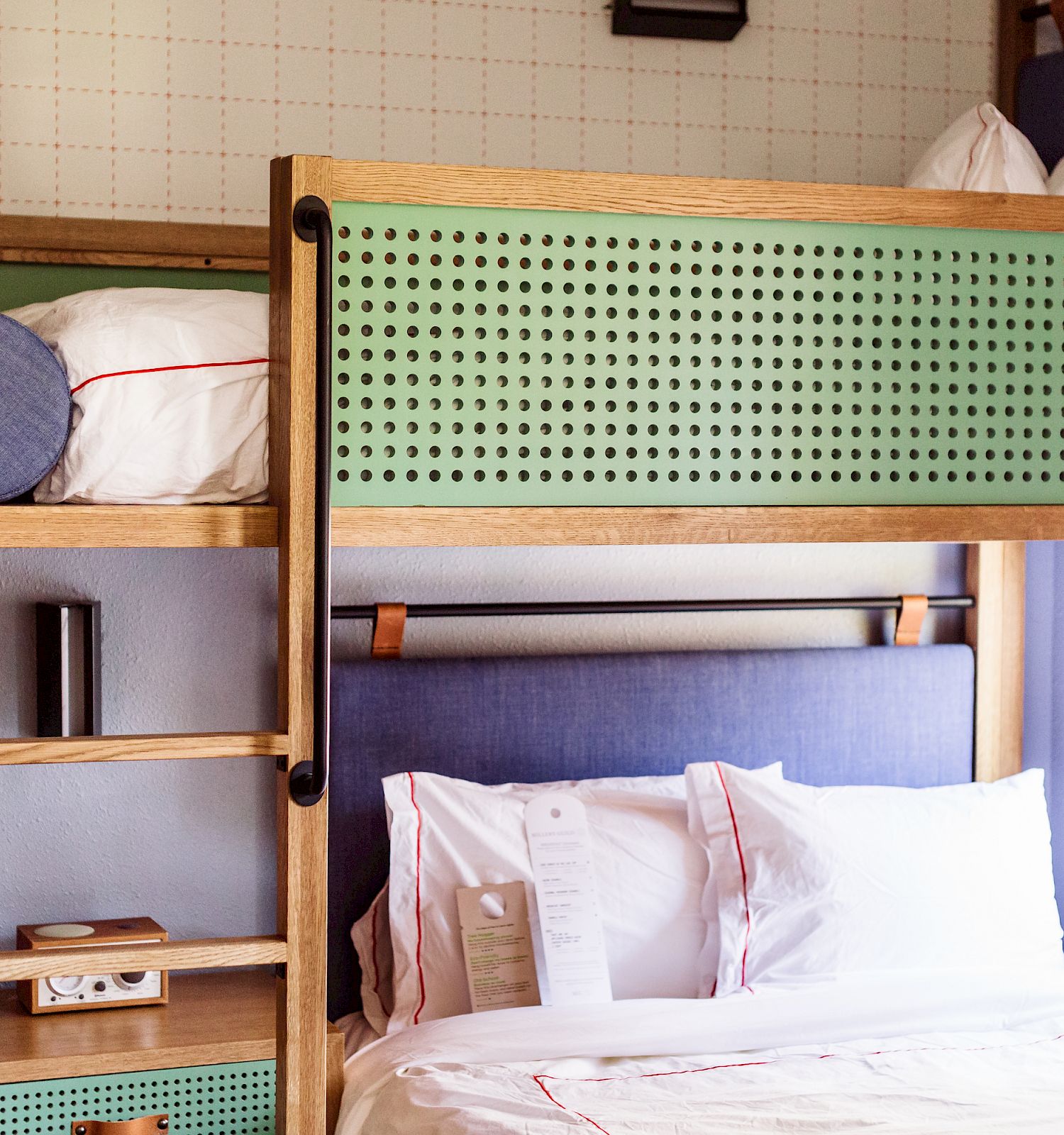 The image shows a modern bunk bed setup with a lower double bed, upper single bed, built-in shelving, and a window beside the beds.