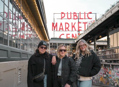 Three individuals are posing for a photo at a market with a large 