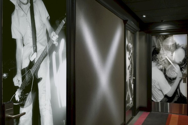 The image shows a hallway decorated with large black-and-white photos of musicians playing instruments, with dark walls and a patterned carpet.