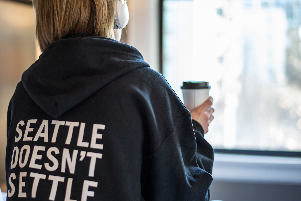 A person wearing headphones and a hoodie with the text 