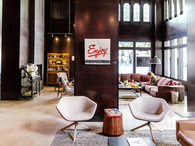 A modern lounge area with stylish chairs, cozy couches, a bookshelf, and a sign that reads 