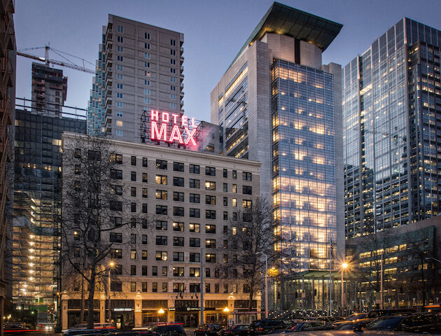 A cityscape with modern skyscrapers and a historic hotel with a neon 
