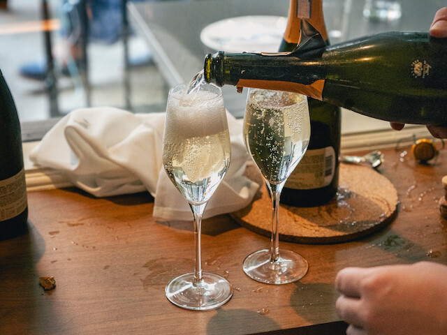 Someone is pouring champagne into two flutes on a restaurant table.