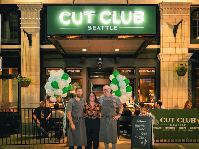 People are posing outside a restaurant named 